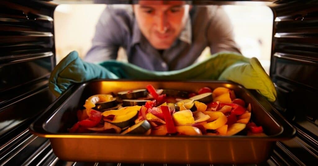 picture of a man putting food in an oven on low